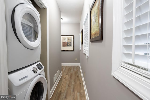 clothes washing area with stacked washer / dryer and light hardwood / wood-style flooring