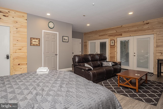 bedroom with wooden walls, french doors, and wood-type flooring