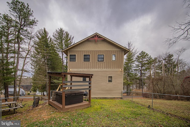 back of property featuring a yard and a hot tub