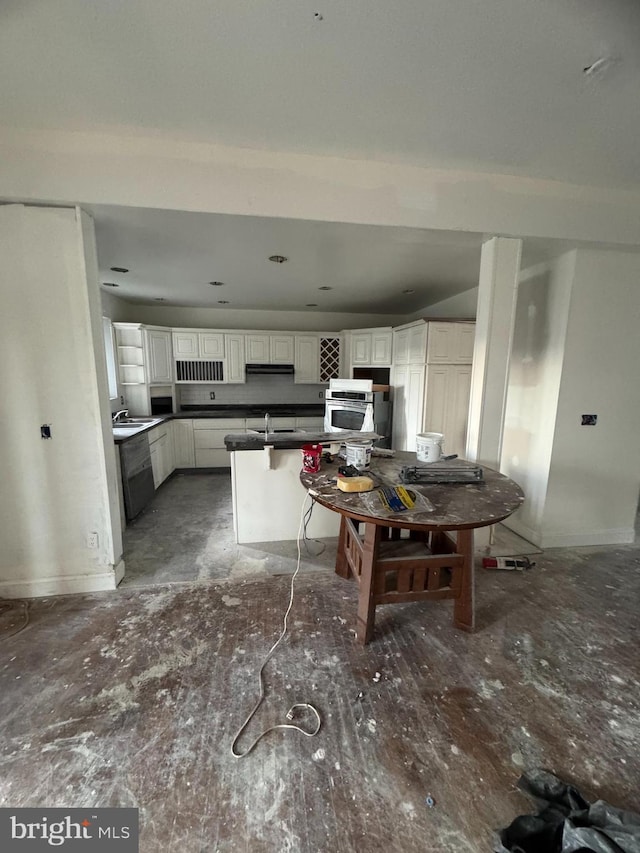 kitchen with kitchen peninsula, ventilation hood, sink, white cabinetry, and oven