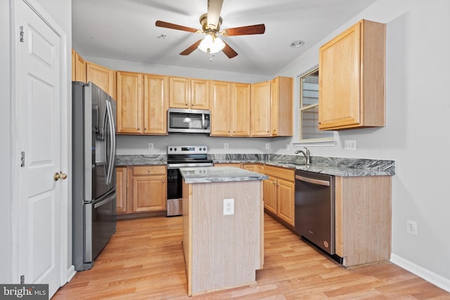 kitchen featuring light brown cabinets, a center island, stainless steel appliances, and light hardwood / wood-style floors