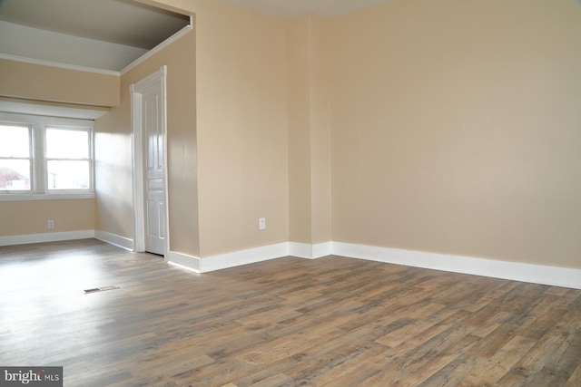 spare room with ornamental molding and dark wood-type flooring