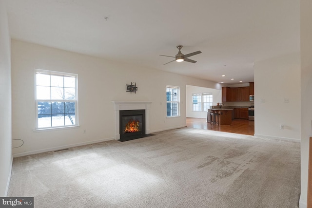 unfurnished living room featuring light carpet and ceiling fan