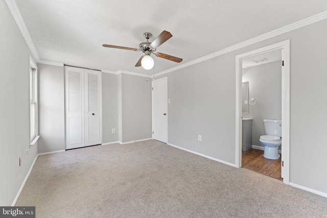 unfurnished bedroom with multiple windows, light carpet, connected bathroom, and ceiling fan