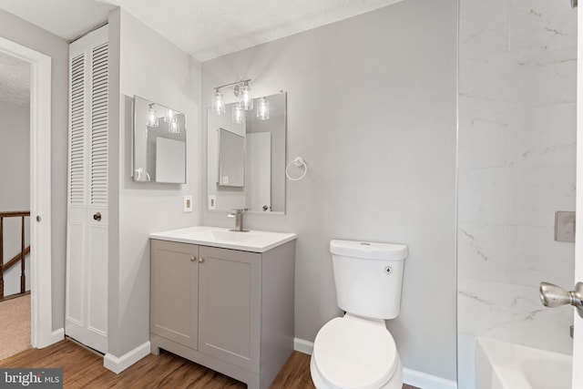 bathroom featuring vanity, a bath, toilet, a textured ceiling, and wood-type flooring