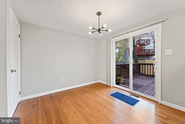 empty room featuring hardwood / wood-style flooring and an inviting chandelier