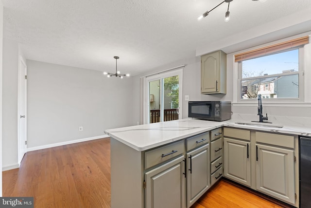 kitchen with gray cabinetry, sink, kitchen peninsula, black appliances, and light wood-type flooring