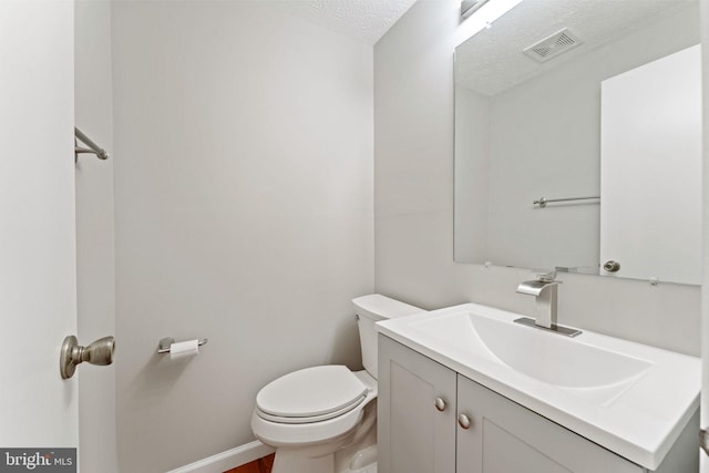 bathroom with vanity, a textured ceiling, and toilet