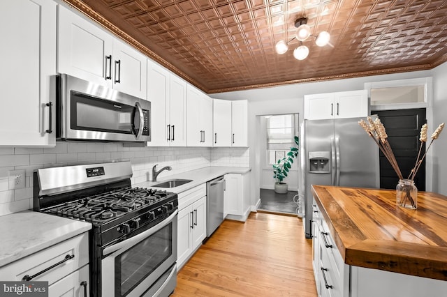 kitchen with butcher block counters, sink, stainless steel appliances, light hardwood / wood-style flooring, and white cabinets