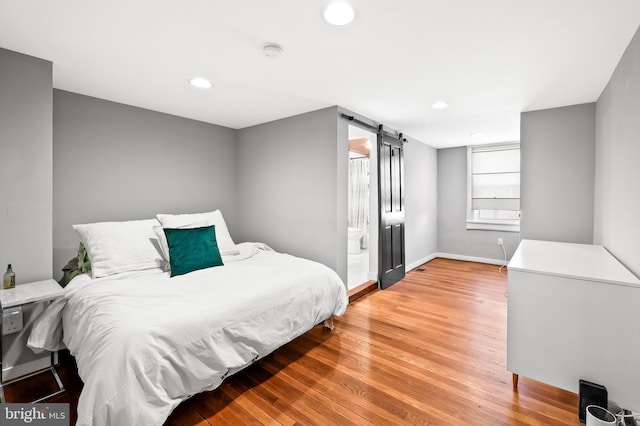 bedroom featuring hardwood / wood-style floors and a barn door