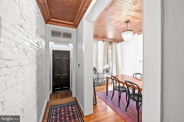 entrance foyer with a chandelier, ornamental molding, wood-type flooring, and wooden ceiling