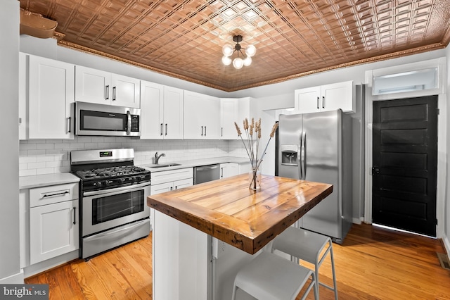 kitchen with butcher block counters, stainless steel appliances, a kitchen island, a kitchen breakfast bar, and white cabinets