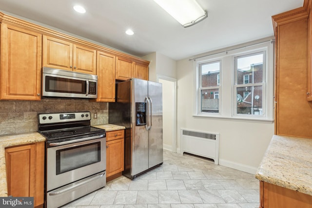 kitchen with decorative backsplash, light stone counters, radiator heating unit, and stainless steel appliances