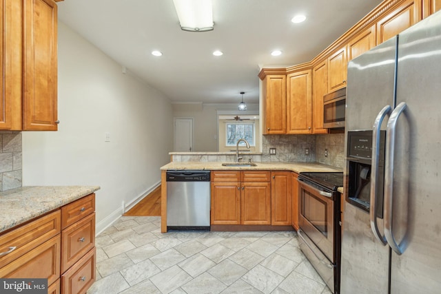 kitchen with light stone countertops, sink, stainless steel appliances, decorative light fixtures, and decorative backsplash