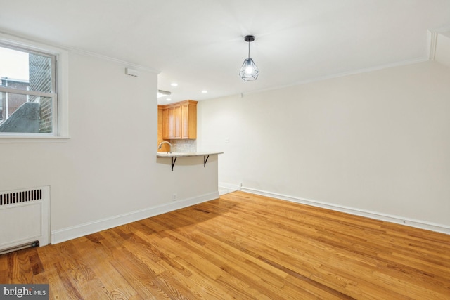 spare room featuring radiator heating unit, light hardwood / wood-style flooring, and ornamental molding