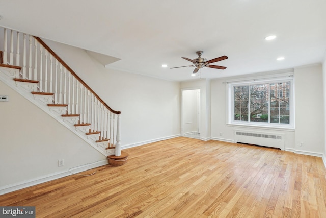 unfurnished living room featuring radiator heating unit, light hardwood / wood-style floors, ceiling fan, and ornamental molding