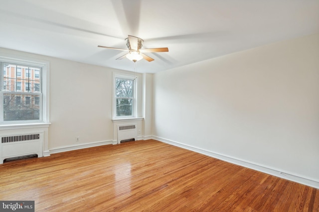 empty room with plenty of natural light, light wood-type flooring, and radiator