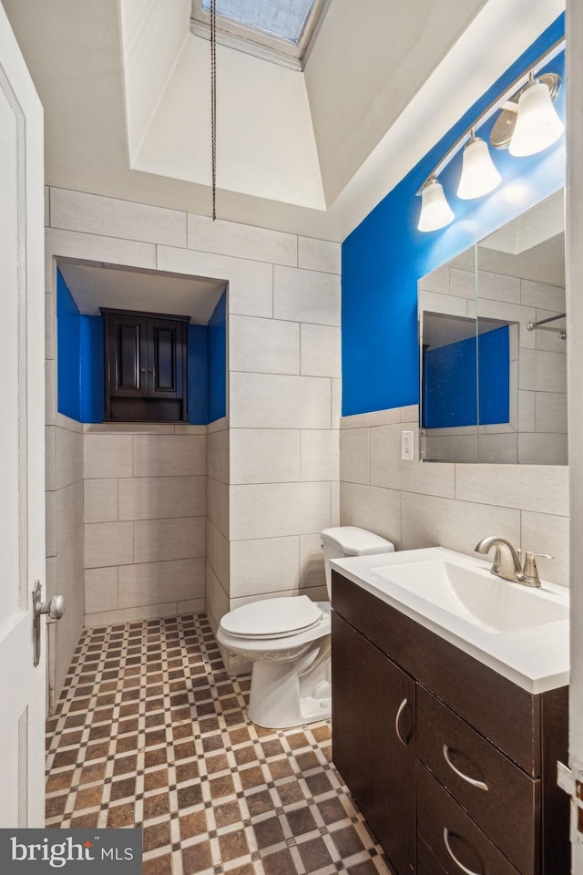 bathroom with vanity, tile walls, and toilet