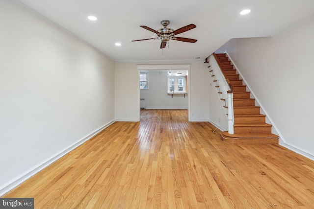 unfurnished living room featuring radiator, ceiling fan, and light hardwood / wood-style flooring