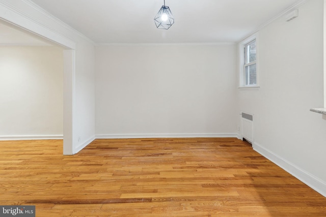 empty room with crown molding, radiator heating unit, and light wood-type flooring