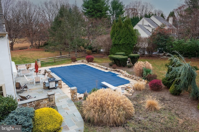 view of pool featuring area for grilling, a diving board, and a patio area