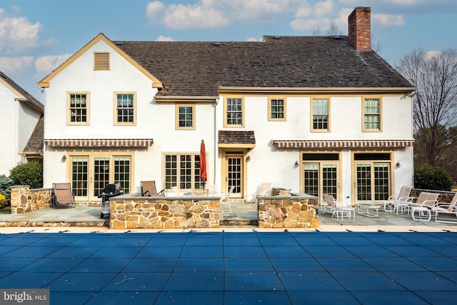 rear view of house featuring a patio area, exterior kitchen, french doors, and a covered pool