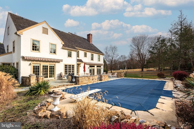 rear view of house with a patio and a covered pool