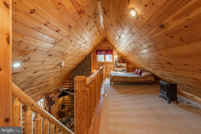 carpeted bedroom featuring wooden ceiling, a wood stove, wooden walls, and vaulted ceiling