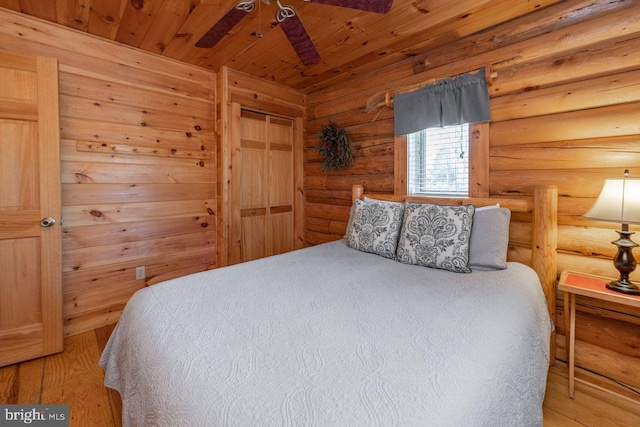 bedroom featuring hardwood / wood-style floors, ceiling fan, wooden ceiling, and log walls