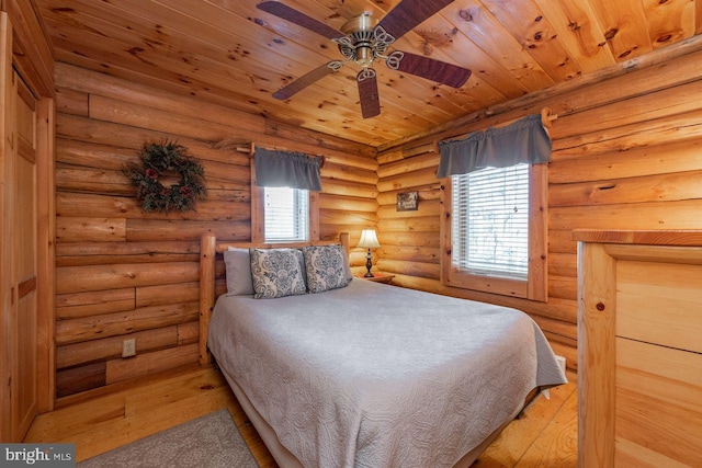 bedroom with log walls, wood-type flooring, multiple windows, and wooden ceiling