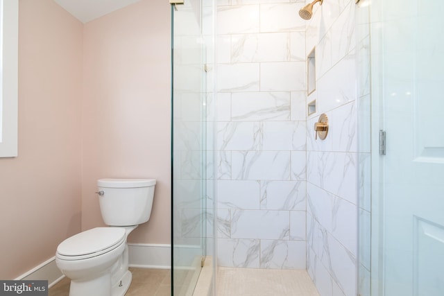 bathroom with a tile shower, tile patterned flooring, and toilet