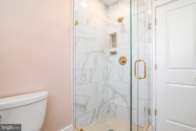 bathroom featuring a shower with door and toilet