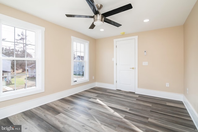 empty room with dark hardwood / wood-style floors, ceiling fan, and a wealth of natural light