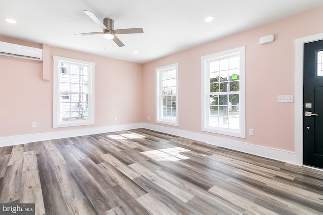 unfurnished room featuring hardwood / wood-style floors, ceiling fan, and an AC wall unit