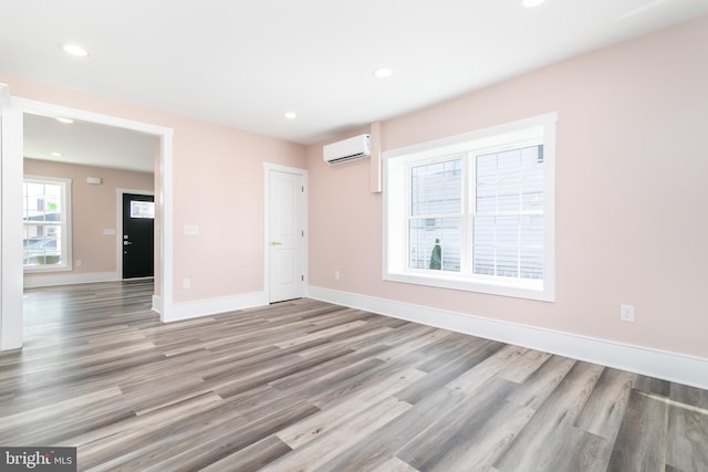 empty room featuring light hardwood / wood-style floors and an AC wall unit