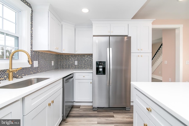 kitchen featuring light wood-type flooring, stainless steel appliances, white cabinetry, and sink