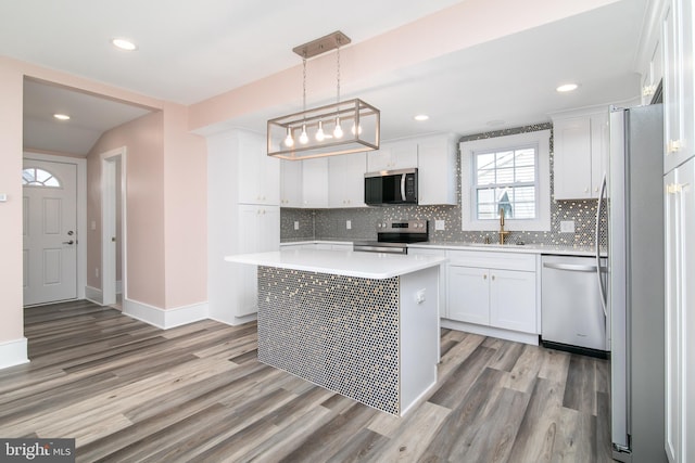 kitchen featuring a center island, stainless steel appliances, pendant lighting, white cabinets, and light wood-type flooring