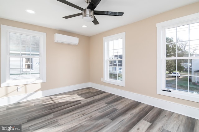 empty room featuring wood-type flooring, a wall unit AC, and ceiling fan