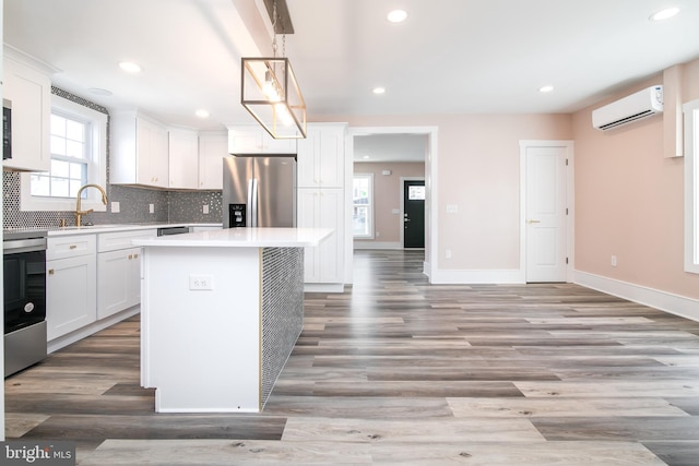 kitchen with a center island, light hardwood / wood-style floors, appliances with stainless steel finishes, and a wall mounted AC