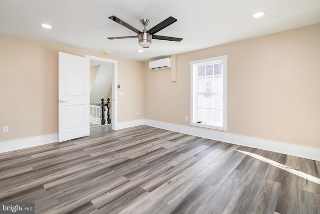 unfurnished room with hardwood / wood-style flooring, ceiling fan, and an AC wall unit