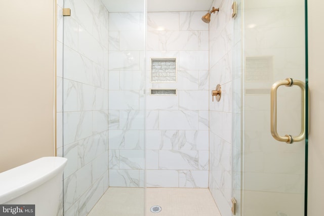 bathroom featuring toilet and a shower with door