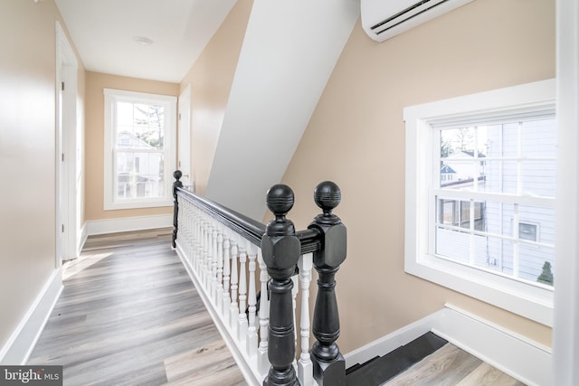 staircase with wood-type flooring and an AC wall unit