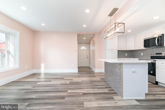 kitchen with white cabinetry, stainless steel appliances, decorative light fixtures, and light hardwood / wood-style floors