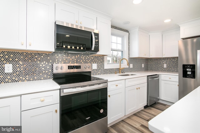 kitchen with tasteful backsplash, white cabinetry, sink, and appliances with stainless steel finishes