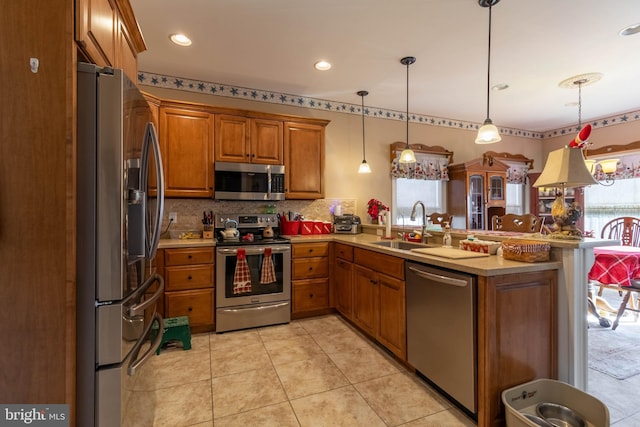 kitchen featuring kitchen peninsula, stainless steel appliances, sink, hanging light fixtures, and light tile patterned flooring