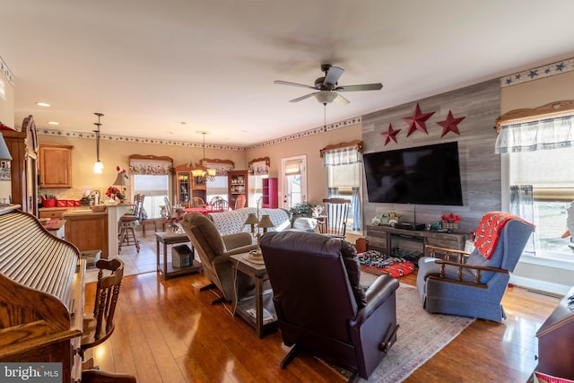 living room featuring ceiling fan with notable chandelier and hardwood / wood-style flooring