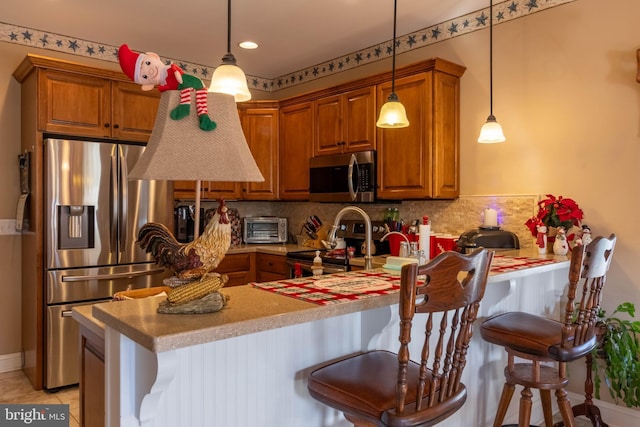 kitchen featuring a kitchen breakfast bar, kitchen peninsula, decorative light fixtures, and appliances with stainless steel finishes