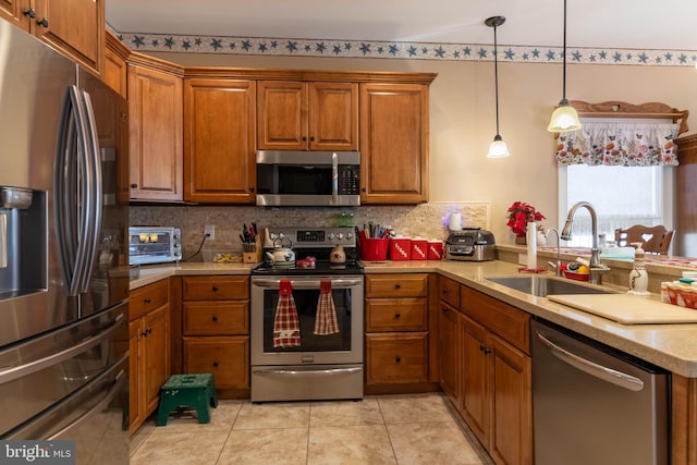 kitchen featuring pendant lighting, backsplash, sink, appliances with stainless steel finishes, and light tile patterned flooring