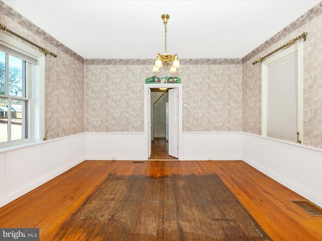 empty room with a wainscoted wall, hardwood / wood-style floors, and visible vents