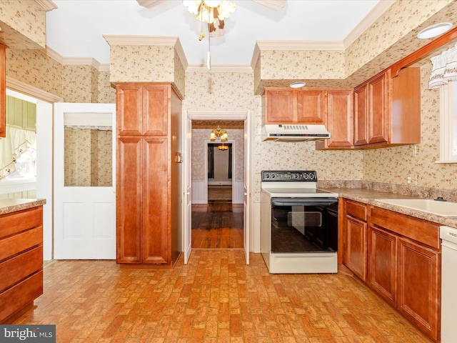 kitchen with brick floor, under cabinet range hood, white appliances, wallpapered walls, and crown molding